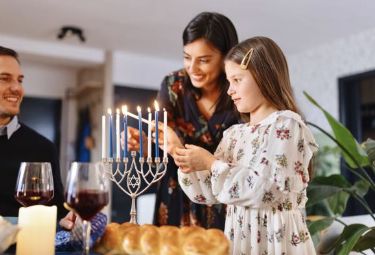 child and mom lighting a menorah as dad smiles and watches - taking time off